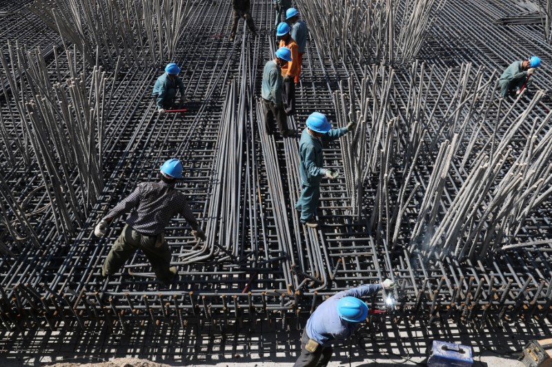 Workers are seen amid steel bars at a construction site of a highway in Zhaotong