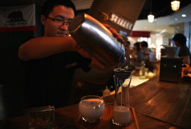 A waiter at a newly opened specialist coffee shop pours an iced-coffee drink for the members of a cupping (tasting) class in Beijing