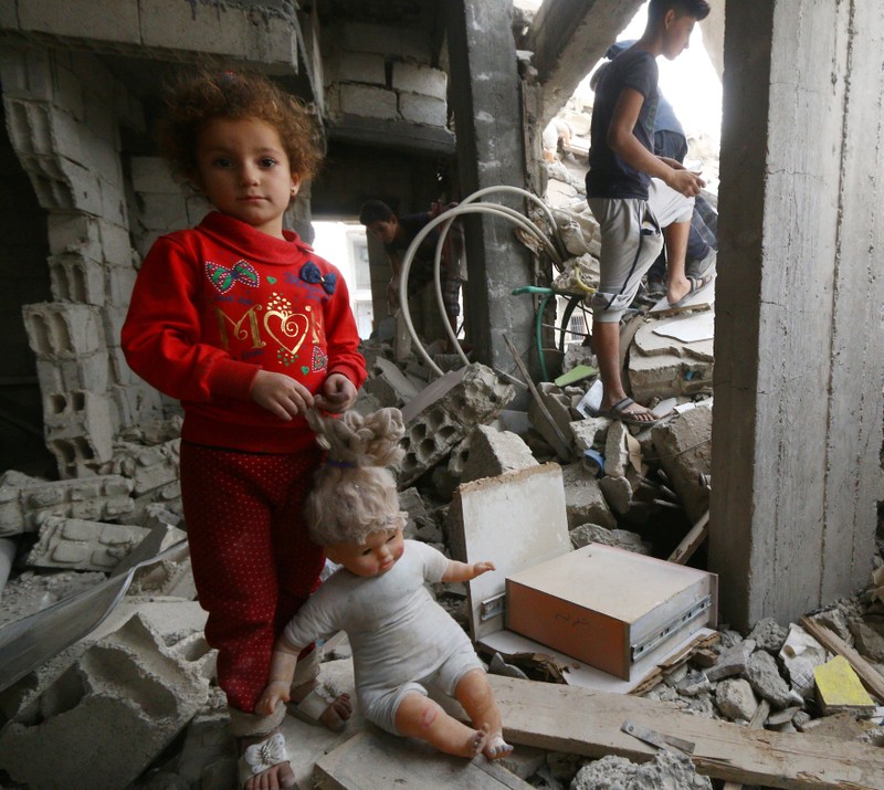 A child stands on the rubble of damaged buildings in Raqqa