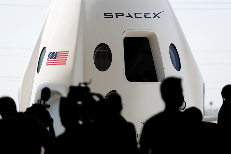 Members of the media gather around a replica of the Crew Dragon spacecraft at SpaceX headquarters in Hawthorne, California