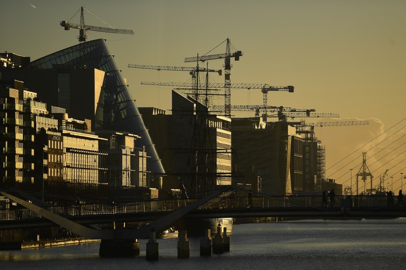 Construction cranes are seen at sunrise in the financial district of Dublin