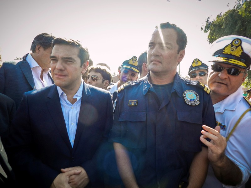 FILE PHOTO: Greek Coast Guard Lieutenant Kyriakos Papadopoulos stands next to Greek Prime Minister Alexis Tsipras during Tsipras's visit to the island of Lesbos