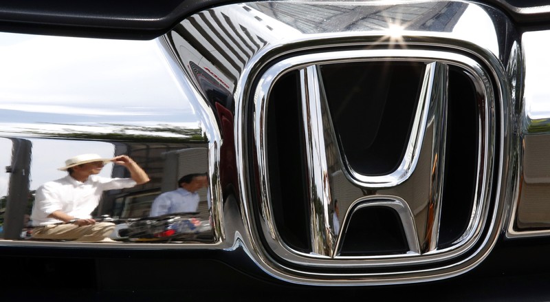 Man are reflected on a Honda Motor car outside the company showroom in Tokyo