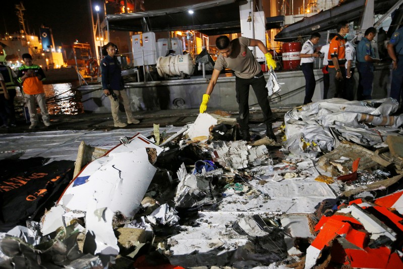 An Indonesian policeman holds wreckage recovered from Lion Air flight JT610 which crashed into the sea, at Tanjung Priok port in Jakarta
