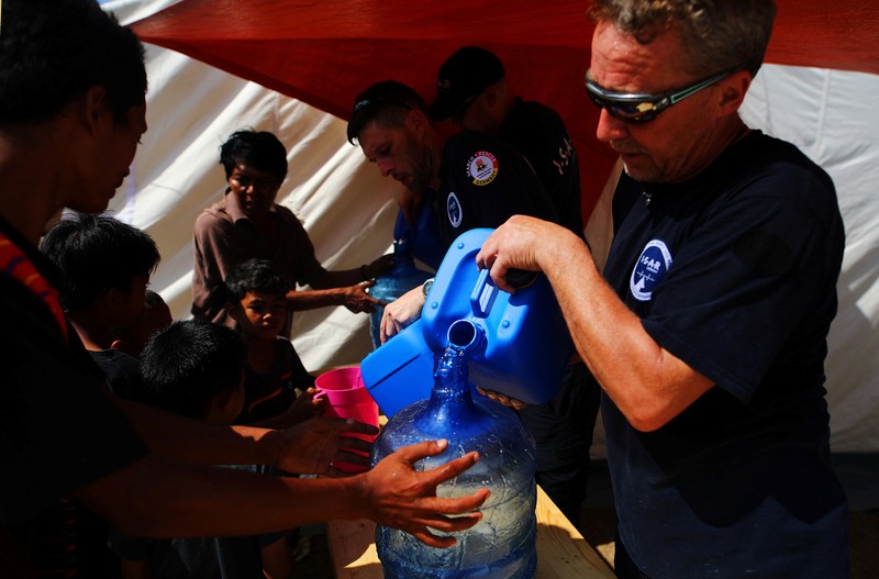 Members of Germany's NGO organisation ISAR-Germany (International Search and Rescue) give purified water to people at a suburb of Palu