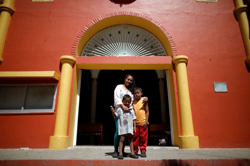 Glenda Escobar, part of a caravan of thousands from Central America en route to the United States, poses for a photograph with her children Adonai and Denzel in San Pedro Tapanatepec