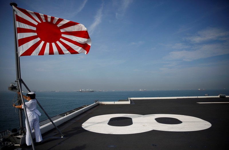A sailor raises the Japanese naval ensign on the deck of Japanese helicopter carrier Kaga before its departure for naval drills in the Indian Ocean