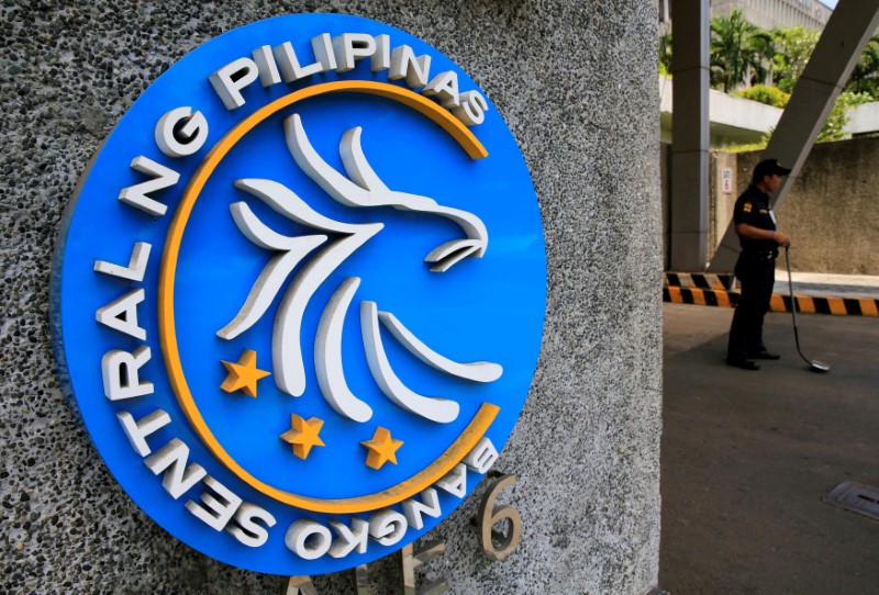 Security guard stands beside a logo of the Bangko Sentral ng Pilipinas (Central Bank of the Philippines) posted at the main gate in Manila