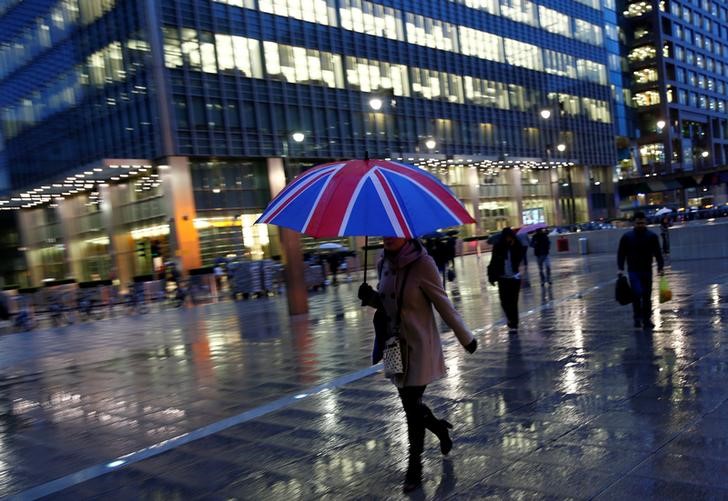 FILE PHOTO: Workers walk in the rain at the Canary Wharf business district in London