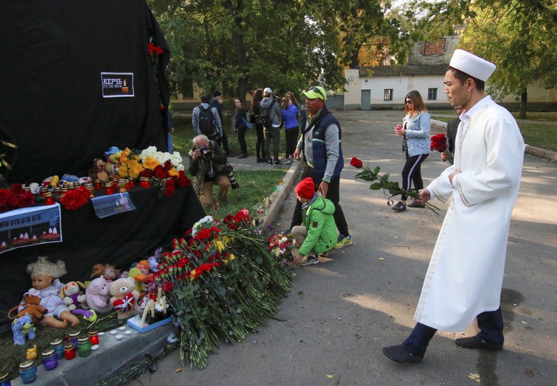 People gather at a makeshift memorial near the scene of an attack on a college in Kerch