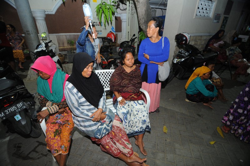 Patients sit at an open area after an earthquake, at Larasati hospital in Pamekasan