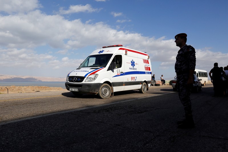 A member of the civil defense stands near an ambulance as they search for survivors after rain storms unleashed flash floods, near the Dead Sea