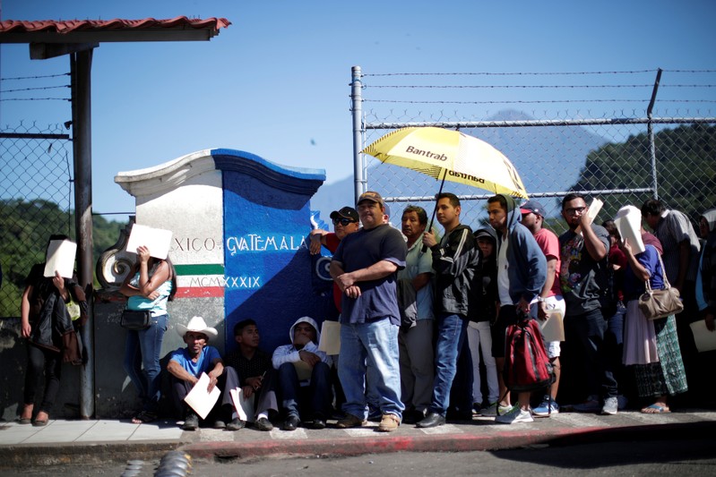 Central American migrants queue at a border connecting Guatemala and Mexico while waiting to cross into Mexico, in Talisman