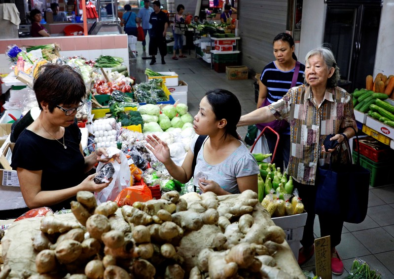 FILE PHOTO: People shop for vegetables at a wet market in Singapore