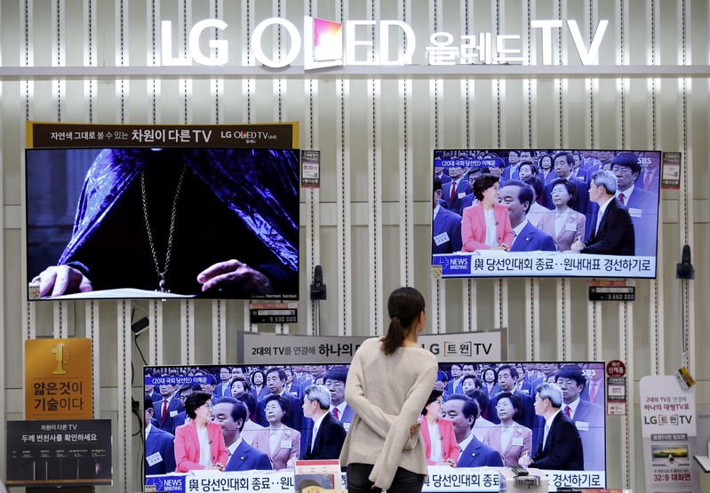 FILE PHOTO: A woman looks at a LG Electronics' organic light-emitting diode (OLED) TV sets, which are made with LG Display flat screens, at its store in Seoul