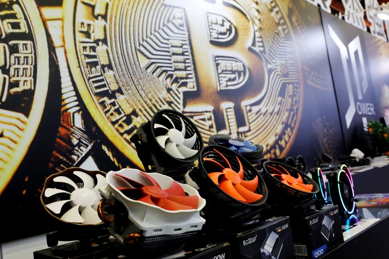 Cryptocurrency mining computer fans are seen in front of bitcoin logo during the annual Computex computer exhibition in Taipei
