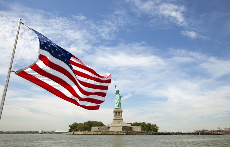 An U.S. flag waves in the wind on a boat near the Statue of Liberty in New York