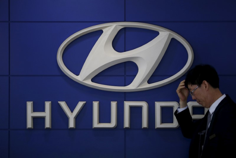 FILE PHOTO: A car dealer stands in front of the logo of Hyundai Motor at its dealership in Seoul