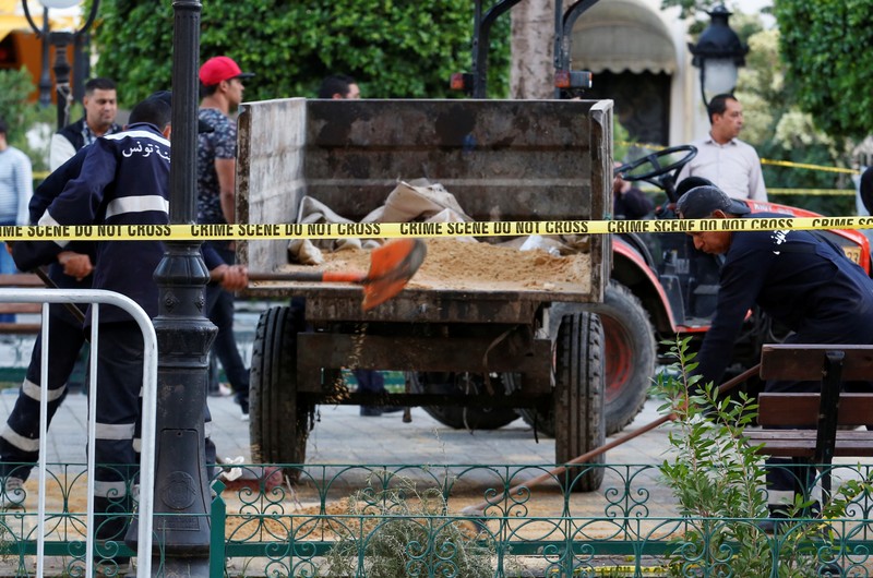 Workers clean the site of an explosion in the center of the Tunisian capital Tunis