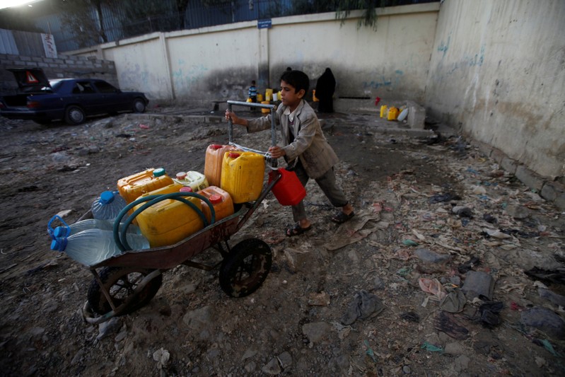FILE PHOTO: A boy pushes a wheelbarrow filled with water containers after collecting drinking water from a charity tap, amid a cholera outbreak, in Sanaa