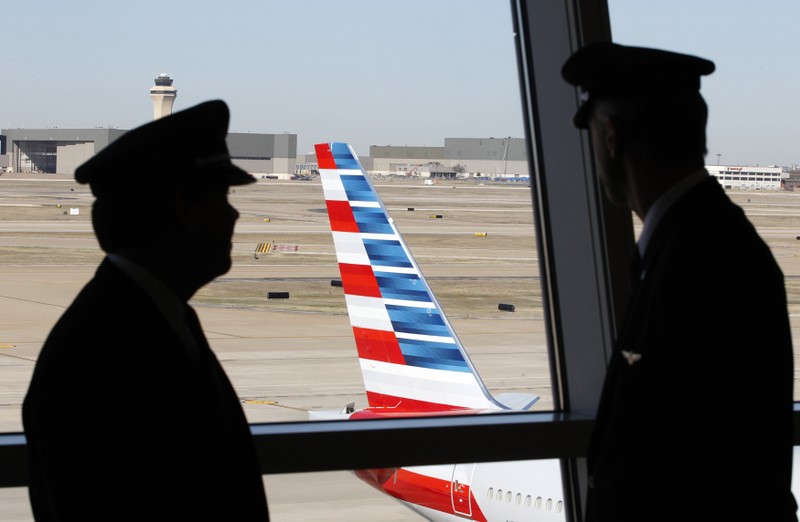Pilots talk as they look at the tail of an American Airlines aircraft f at Dallas-Ft Worth International Airport