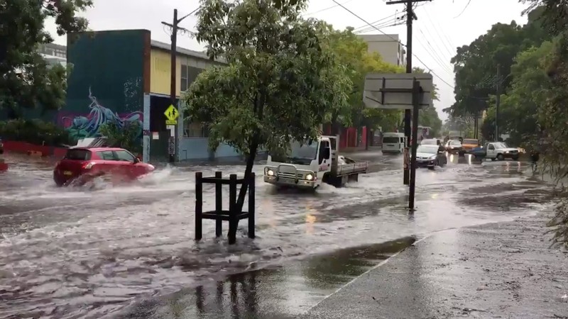 Vehicles drive on a flooded street in Sydney