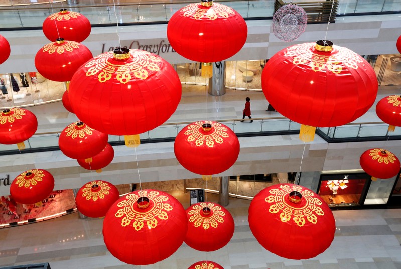 FILE PHOTO: A shopper is seen through large lantern decorations at a shopping mall in Beijing