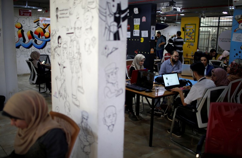 Members of 'We Are Not Numbers' team work on laptops in an office in Gaza City