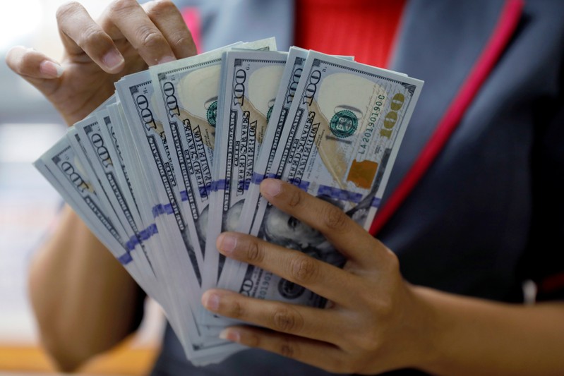 An employee counts U.S. dollar banknotes at a currency exchange office in Jakarta