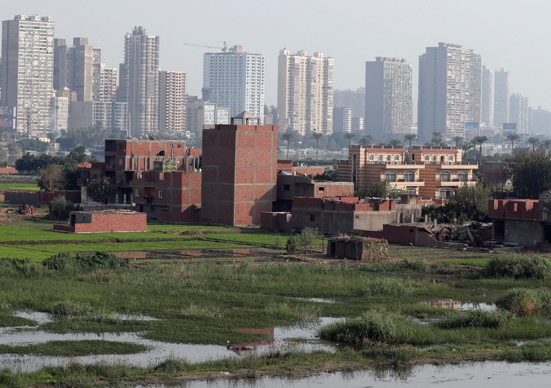 A view of houses and farmland on an island on the River Nile in front of high-rise buildings in Cairo