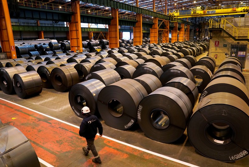 FILE PHOTO: A worker walks past steel rolls at the ArcelorMittal steel plant in Sestao