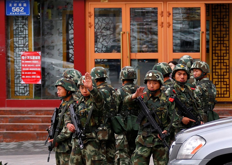 FILE PHOTO: Paramilitary policemen gesture to stop a photographer from taking pictures as they stand guard after explosives attack hit downtown Urumqi on Thursday, in Xinjiang Uighur Autonomous Region