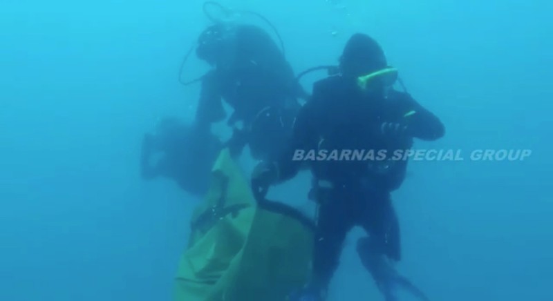 Divers collect debris in a bag in the search area for Lion Air's flight JT610 airplane, in Indonesia