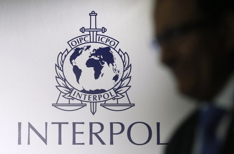 FILE PHOTO - A man passes an Interpol logo during the handing over ceremony of the new premises for Interpol's Global Complex for Innovation in Singapore