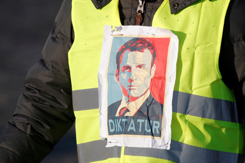 A man wearing a yellow vest, a symbol of a French drivers' protest against higher fuel prices, attends the demonstration with an image of French president Emmanuel Macron