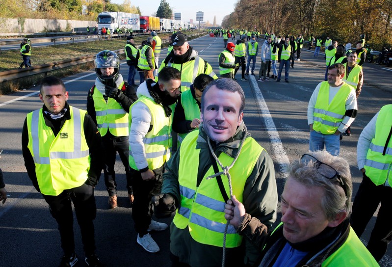 FILE PHOTO: A man wears a mask with the likeness of French president Emmanuel Macron as people take part in the nationwide yellow vests demonstrations, a symbol of a French drivers' protest against higher fuel prices, in Haulchin