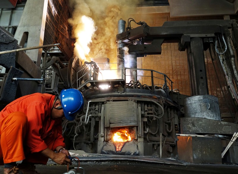 FILE PHOTO: A Man works in front of a furnace at a steel plant of Dalian Special Steel Co Ltd. in Dalian, Liaoning