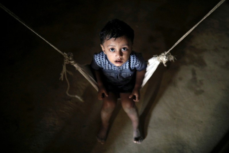 A Rohingya refugee child reacts to the camera while sitting on a cradle at the Balikhali camp in Cox's Bazar