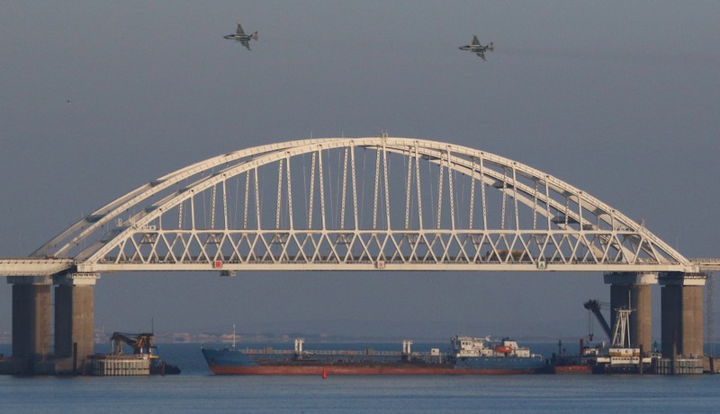 Russian jet fighters fly over a bridge connecting the Russian mainland with the Crimean Peninsula with a cargo ship beneath it after three Ukrainian navy vessels was stopped by Russia from entering the Sea of Azov via the Kerch Strait in the Black Sea