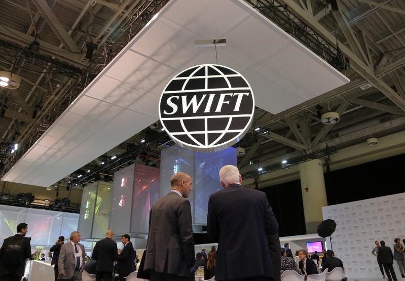 Delegates chat under the logo of global secure financial messaging services cooperative SWIFT at the SIBOS banking and financial conference in Toronto
