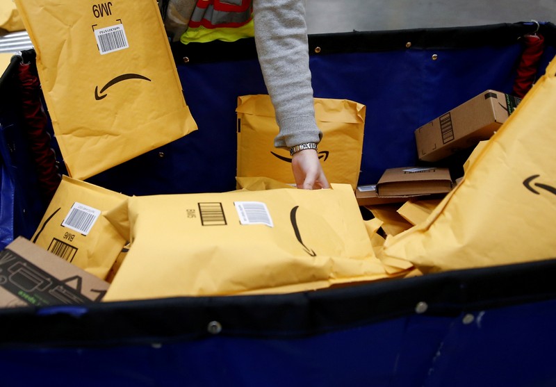 FILE PHOTO: Area manager Wells retrieves packages to put them on a conveyor line for scanning and labeling at the Amazon fulfillment center in Kent