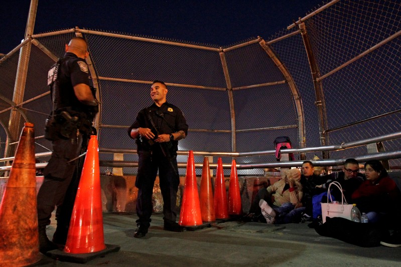 FILE PHOTO: Border police look on as a group of Central Americans and Cubans hoping to apply for asylum wait at the border on an international bridge between Mexico and the U.S., in Ciudad Juarez