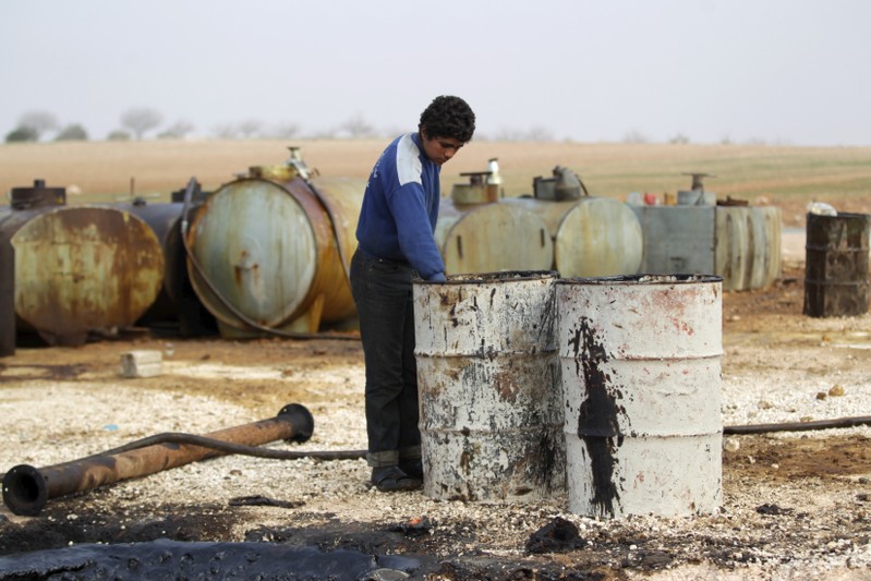 A youth works at a makeshift oil refinery site in Marchmarin town, southern countryside of Idlib, Syria