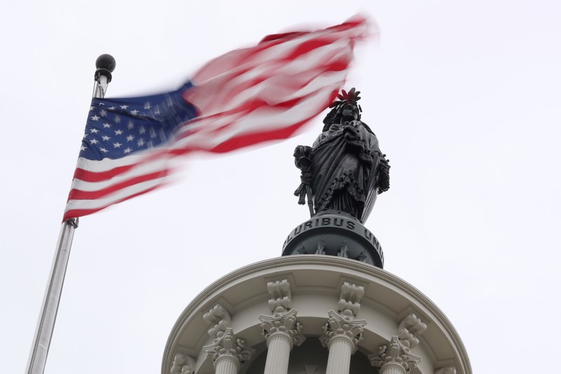 The U.S. flag flies near the Statue of Freedom atop the U.S. Capitol in Washington