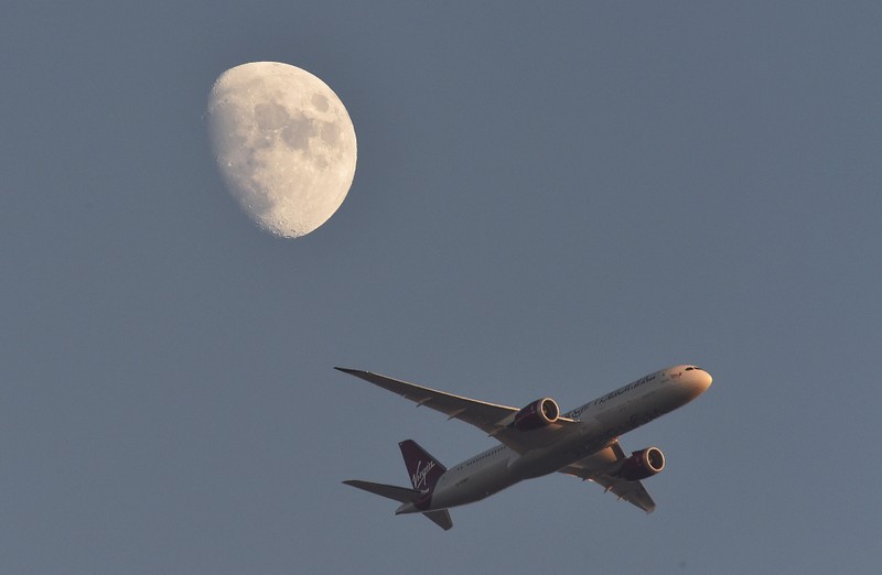 FILE PHOTO: A Virgin Atlantic passenger plane flies in the sky with the moon seen in the background, in London, Britain