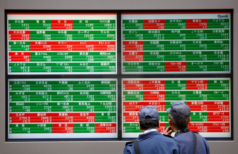 Men look at stock quotation boards outside a brokerage in Tokyo
