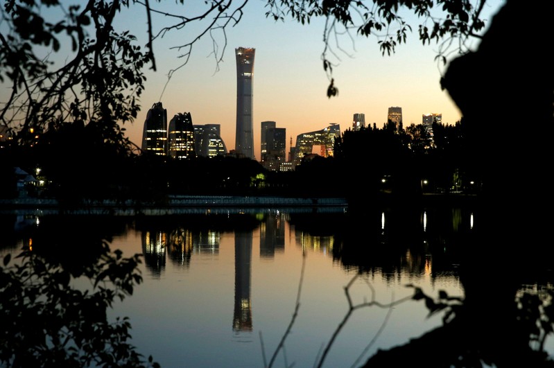 FILE PHOTO: The cityscape of the Beijing Central Business District is reflected in a pond during sunset
