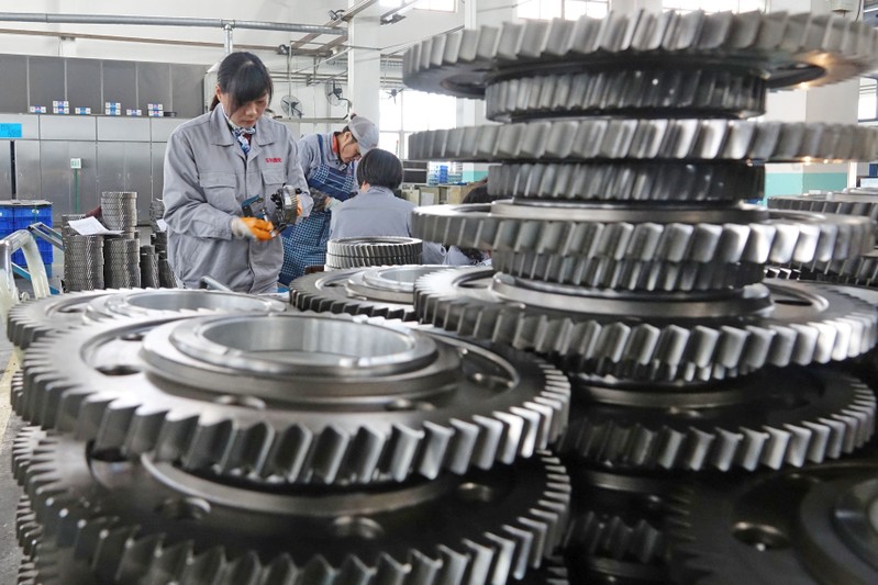 FILE PHOTO: Workers inspect engine gears at a company under Dongbei Special Steel Group in Yantai
