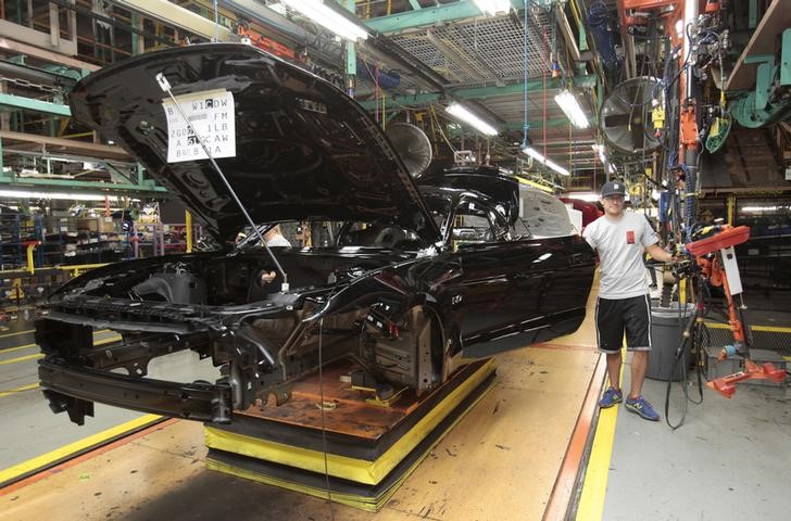 A Ford Motor assembly worker works on the frame of a 2015 Ford Mustang vehicle at the Ford Motor Flat Rock Assembly Plant in Flat Rock, Michigan