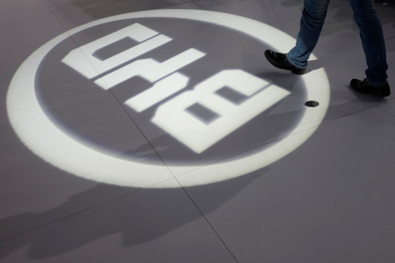 FILE PHOTO: A man walks past a light flashing on the floor in the shape of the logo of BYD Auto during the media preview of the 10th China International Automobile Exhibition in Guangzhou
